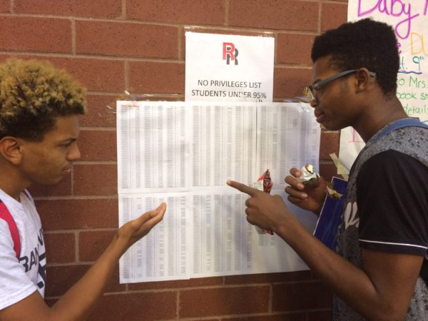Junior Roman Edwards (left) and senior Keshawn Bradshaw (right) look at the No Privileges List posted outside the Commons. If you are ineligible for the dance due to attendance, your ID number can be found on this list. (Savannah Lyman)