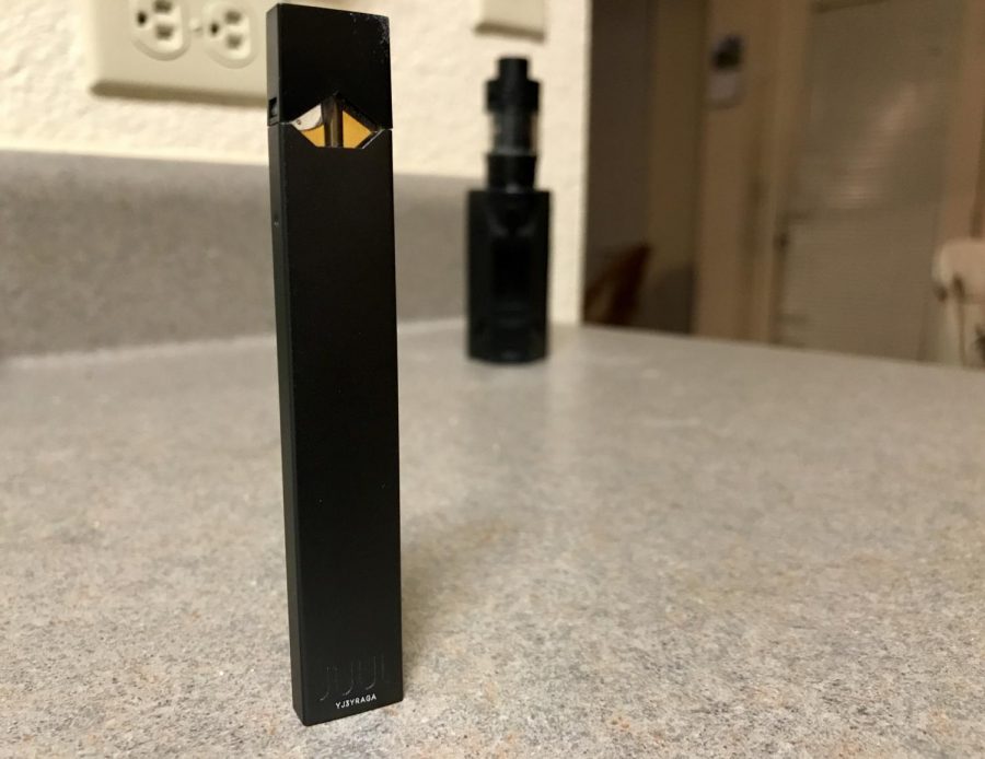 Juul+is+a+popular+brand+of+e-cigarette.+Behind+it+is+a+much+larger+vape+mod%2C+capable+of+holding+much+more+of+the+nicotine-filled+juice.+%28Dylan+Tressider%29