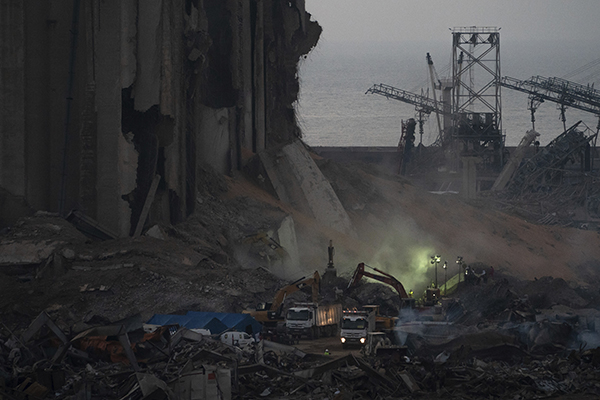 Trucks and workers sift through rubble shortly after the explosion in Lebanon in an effort to start searching and cleaning. (Infoplease)