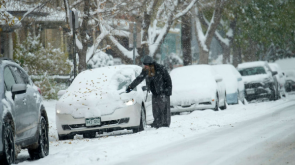 A motorist clears snow from a vehicle after a winter storm dumped up to a foot of snow in some Front Range communities, Oct. 29, 2023, in Denver. (ABC News)